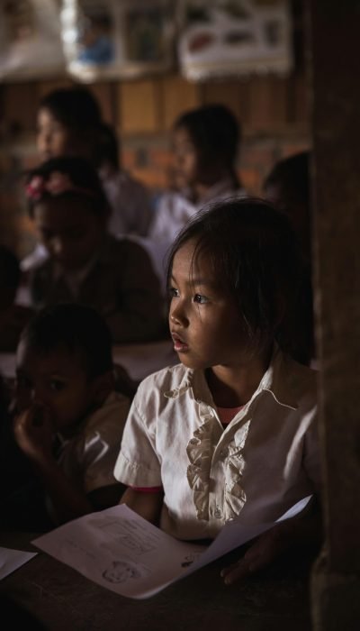 Focused children in a dimly lit classroom attentively listening and studying.